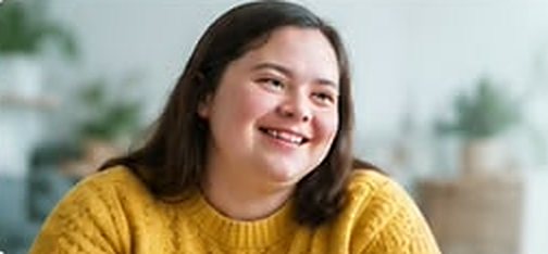 Smiling young woman in a yellow jumper at home
