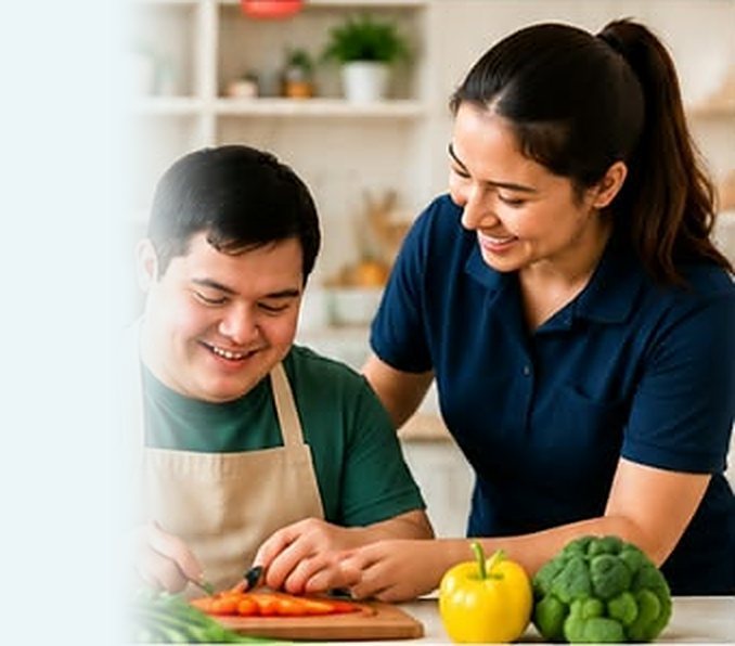 Young man chopping vegetables with a support worker in the kitchen