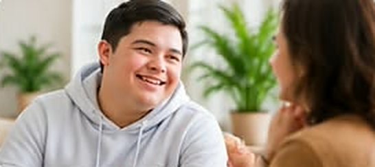Young man in a grey hoodie chatting happily with a support worker