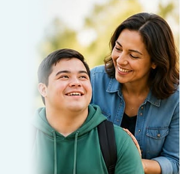 Young man in a green hoodie smiling with a supportive carer